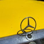 a mercedes emblem on the hood of a yellow car